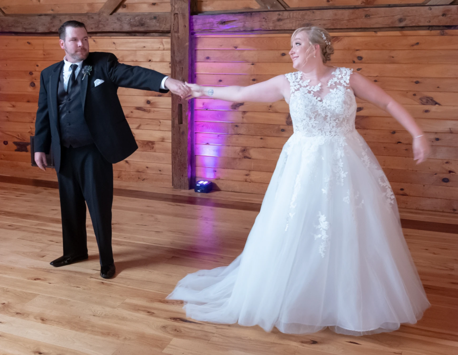 Bride and groom extending their arms during a choreographed barn wedding spin