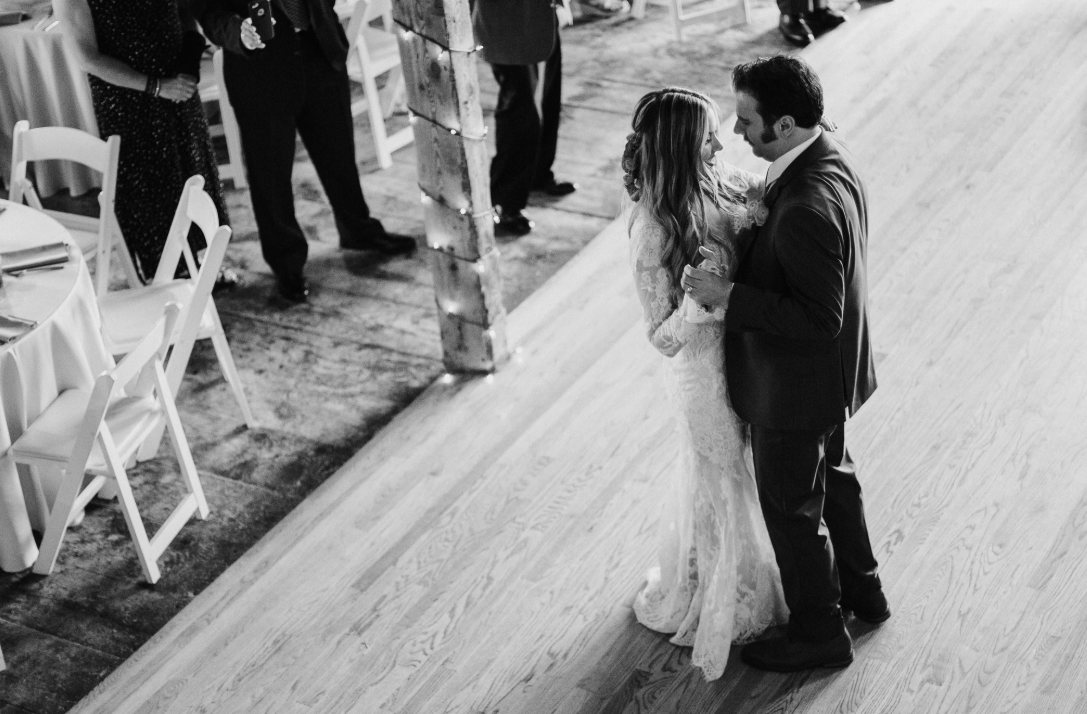 Black-and-white overhead photograph of newlyweds dancing at a barn wedding