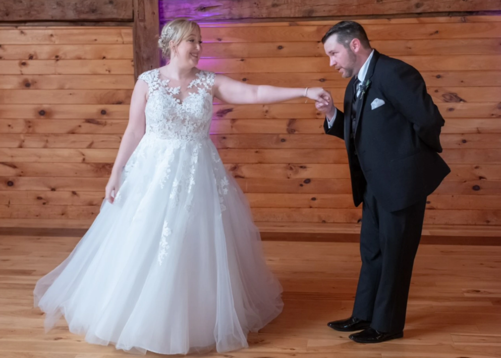 Groom kissing his bride's hand during their barn wedding choreography