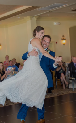 Groom in a blue suit lifting his bride during their ballroom first dance