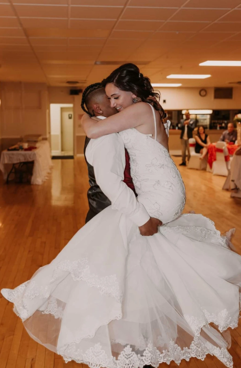 Newlyweds laughing during a joyful lift and spin on the dance floor